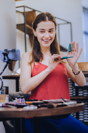 Showing mascara. Smiling beautiful beauty blogger showing her best eye mascara her followersの写真素材