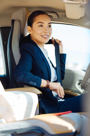 Joyful mood. Joyful happy woman smiling while fastening her seatbeltの写真素材