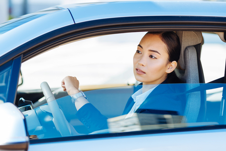 Smart nice woman looking at the time while driving in the carの写真素材