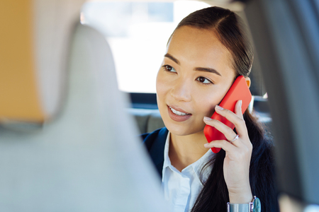 Business issues. Positive Asian businesswoman smiling while talking on the phoneの写真素材