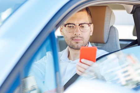 New message. Smart serious man holding his smartphone while checking new messages