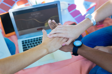 Achieving success. Prosperous young entrepreneurs holding their hands together feeling happy achieving successの写真素材