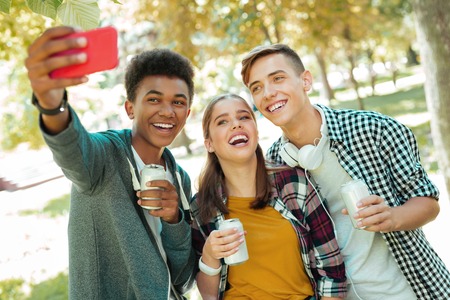 Broad smile. Three young personalities smiling broadly while making photo spending free time...