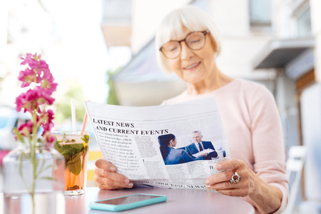 Excellent news. Selective focus of fresh newspaper read by senior women who smilingの写真素材