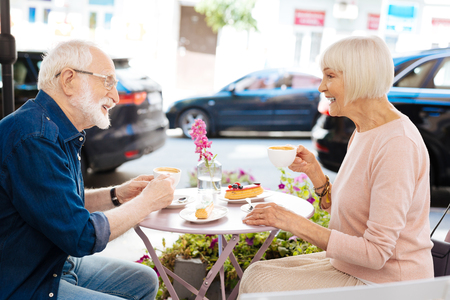 Pleasant conversation. Energetic senior couple sitting at cafe and drinking coffeeの写真素材