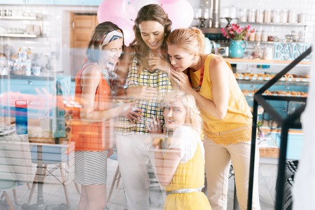 Ears to tummy. Three loving sisters feeling delightful while putting their ears to pregnant tummyの写真素材