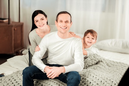 Family time. Joyful delighted family sitting together while smiling to you
