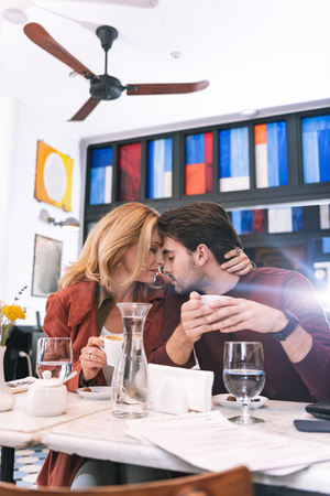 Emotional connection. Musing adorable couple drinking coffee and caressingの写真素材