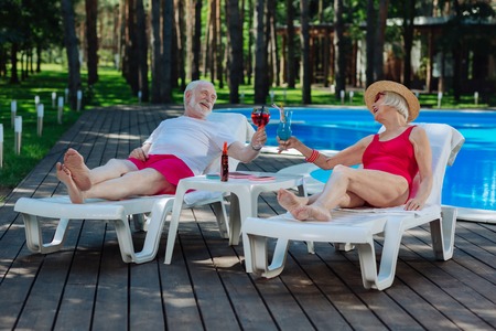 Retired couple. Couple of retired people feeling unbelievable while having rest lying on deck chairの写真素材