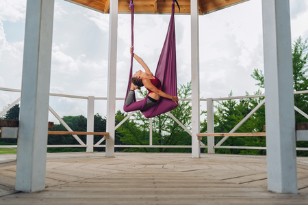 Aerial yoga. Beautiful woman with nice body and abs feeling calm and rested while practicing aerial yogaの写真素材