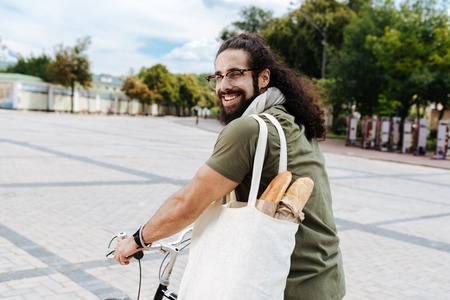 Positive mood. Delighted joyful man smiling to you while going home from the supermarketの写真素材