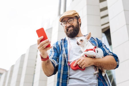 Red smart watch. Modern freelancer wearing red smart watch typing message while walking the city with dogの写真素材