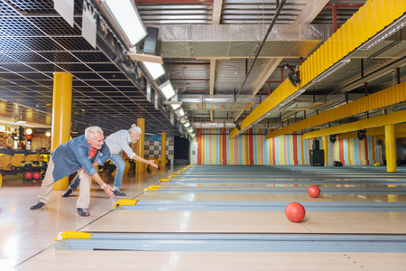 Who is the best. Delighted positive men taking part in the bowling competition while deciding who is the bestの写真素材