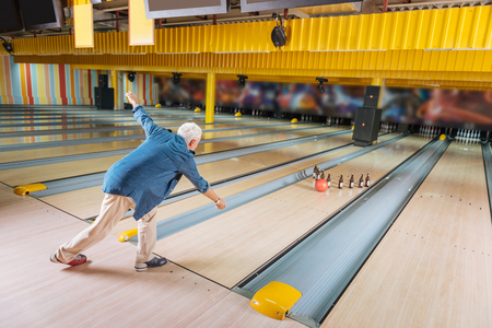 Fun game. Nice skilled man hitting beer bottles while playing bowlingの写真素材