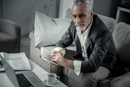 Join me. Concentrated senior man turning head while making noticesの写真素材