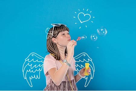 Soap bubbles. Calm relaxed teenage girl blowing bubbles while having free timeの写真素材