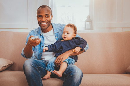 Our recreation. Inspired loving daddy holding a remote control and babysitting his sonの写真素材