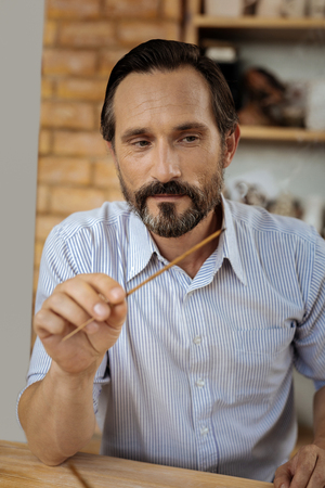 Inspired man. Dark-eyed bearded man feeling inspired while using aroma sticks sitting in his workroomの写真素材