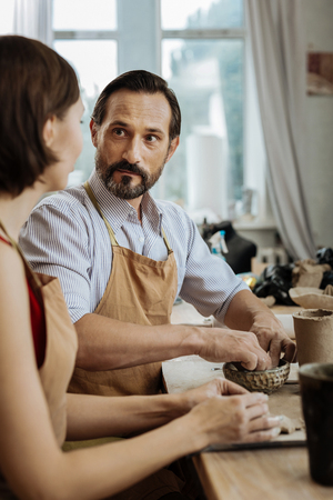 Talking to wife. Dark-eyed ceramist feeling calm and free while talking to his wife in the process...