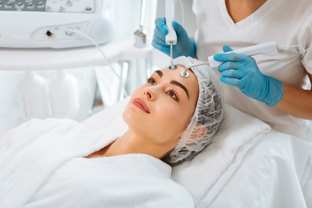 Beauty therapy. Positive nice woman smiling while trying a new beauty procedure