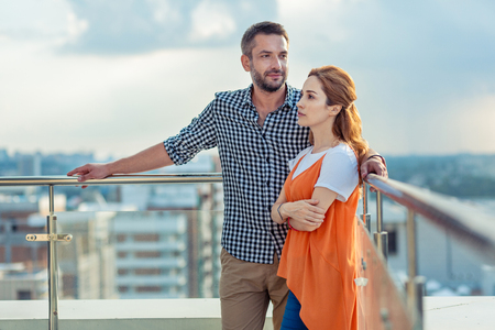 Beautiful view. Pleasant nice couple standing together while being on the top of the buildingの写真素材