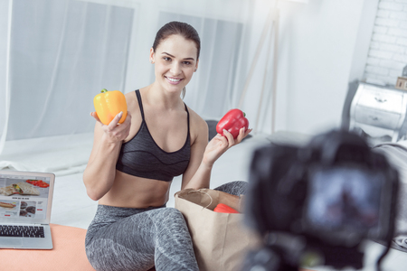Tasty and useful. Delighted cheerful woman smiling to the camera while showing pepperの写真素材