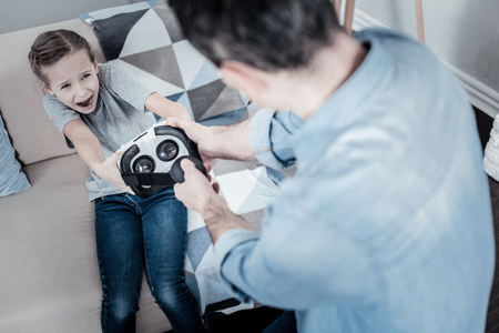 Family problems. Angry stressed child being unsatisfied while taking headphones from the fatherの写真素材