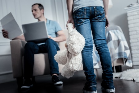 Pay attention. Offended upset child holding a toy while standing in front of the fatherの写真素材