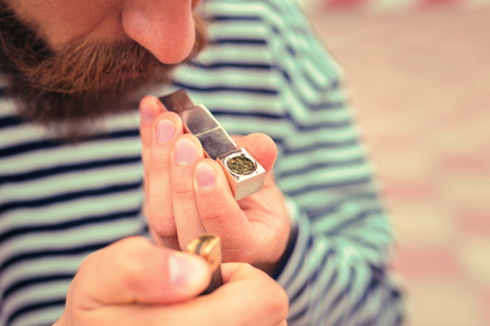 Man smoking pipe. Laconic image of bearded man holding tiny metal pipe and lighting tobacco in it...