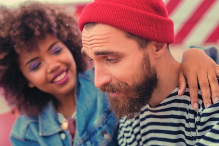 Feeling better. Cheerful young girl kindly smiling to her exhausted boyfriend after having long party with himの写真素材