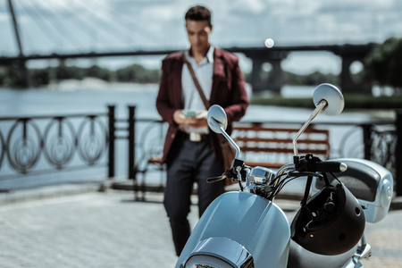 Quick vehicle. Selective focus of shiny steel motorbike standing and guy coming close to itの写真素材