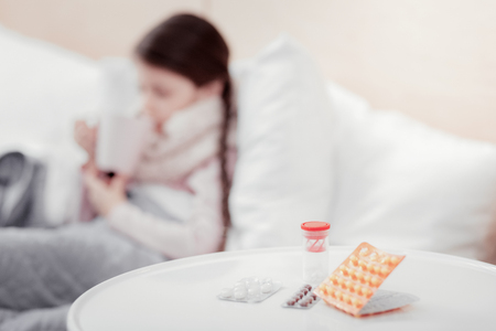 Doctors instruction. Close up of various prescribed pills lying on the table with little girl on the backgroundの写真素材
