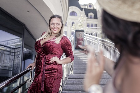 Beautiful style. Joyful plump woman wearing a red velvet dress while posing for a photoの写真素材