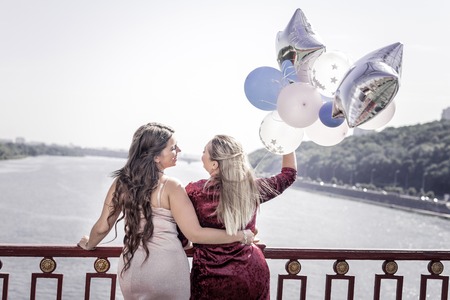 Best friends. Positive joyful women hugging each other while standing together on the bridgeの写真素材