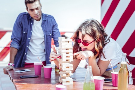 Be careful. Charming female expressing positivity while playing table game in group of her friendsの写真素材