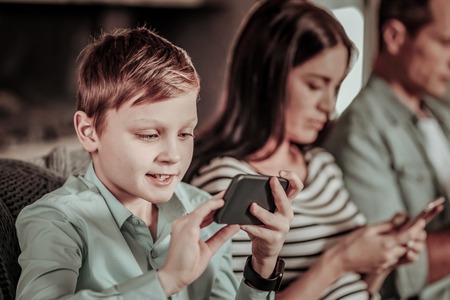 Little gamer. Silhouette of female person that sitting between her males and typing messageの写真素材