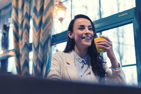 Fresh juice. Charming brunette expressing positivity while thinking about her boyfriendの写真素材