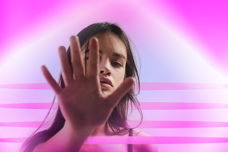 Stop shooting. Pensive nice woman posing on background and stretching handの写真素材