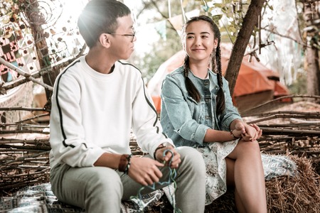 Pleasant smile. Pretty Asian female expressing positivity while looking at her boyfriendの写真素材