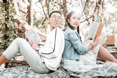 I am here. Pleased young male person keeping smile on his face while talking about his bookの写真素材