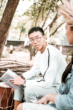 Asian people. Concentrated brunette man holding book while looking asideの写真素材