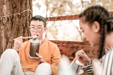 Asian food. Serious brunette male leaning on tree while being deep in thoughtsの写真素材