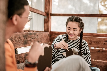Dinner time. Beautiful female person expressing positivity while looking into box with foodの写真素材