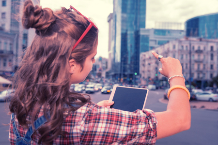 Hair bun. Dark-haired girl with nice hair bun wearing squared shirt standing and looking at nice business centerの写真素材