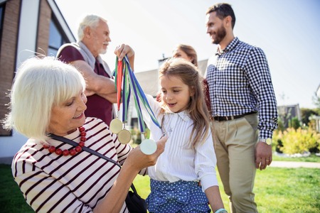My medals. Charming girl keeping smile on her face while holding her medalsの写真素材