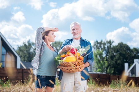 Satisfied wife. Smiling blonde-haired wife feeling satisfied after gathering harvest with her handsome bearded husbandの写真素材