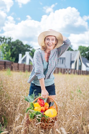 Harvesting vegetables. Appealing emotional woman wearing squared shirt feeling extremely happy after harvesting vegetablesの写真素材