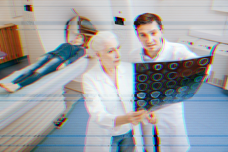 Discussing MRT. Experience medical workers standing not far from the patient and thoughtfully looking at the MRT resultsの写真素材