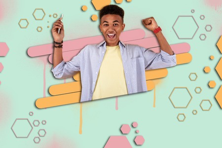 Prize winner. Happy mulatto boy standing in front of graphic ground feeling extremely cheerful after winning prize in online gameの写真素材