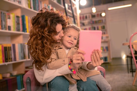 Our selfie. Pretty female person kissing her kid while posing on cameraの写真素材